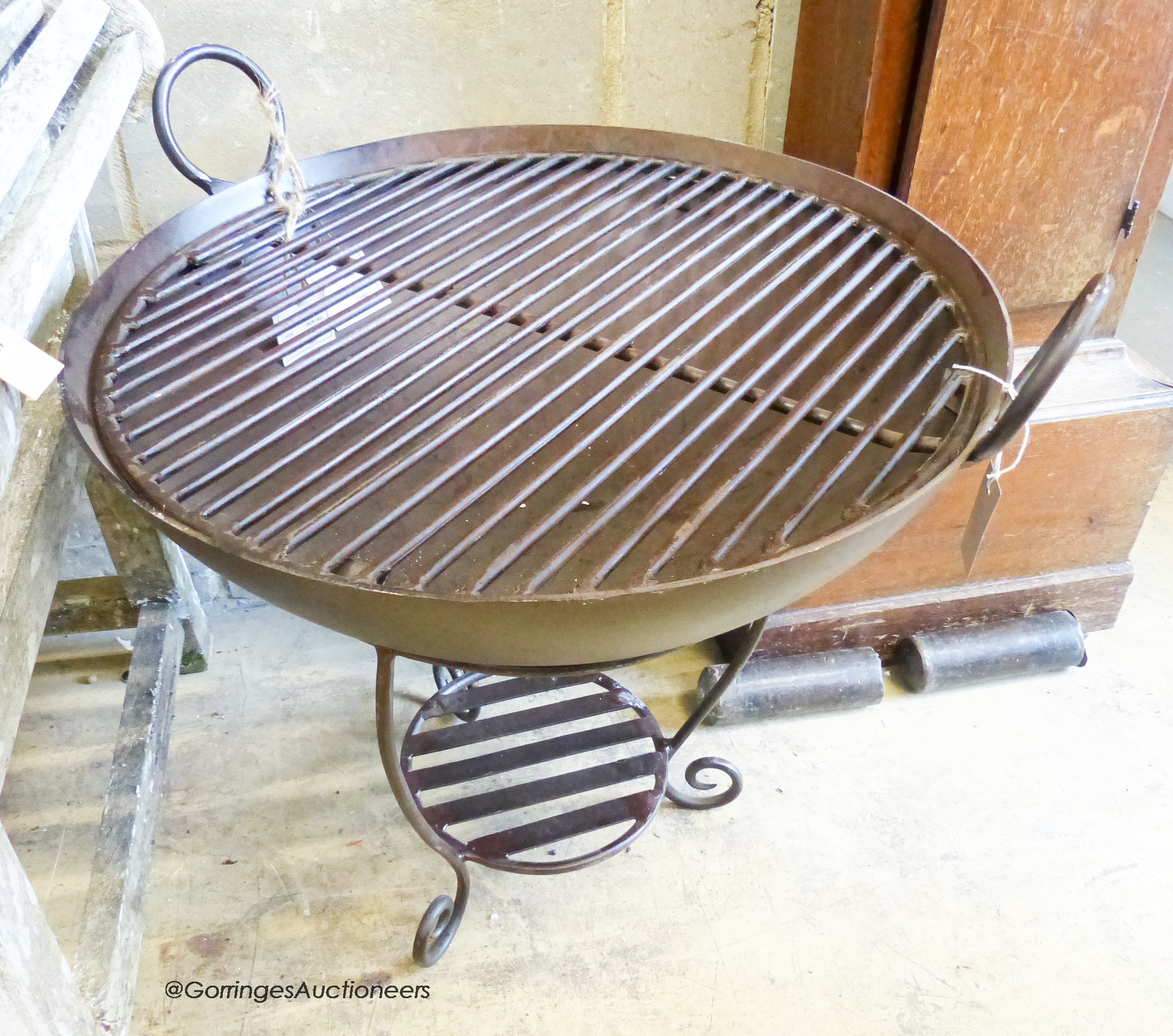A wrought iron garden fire pit on stand with grill, diameter 69cm, height 65cm